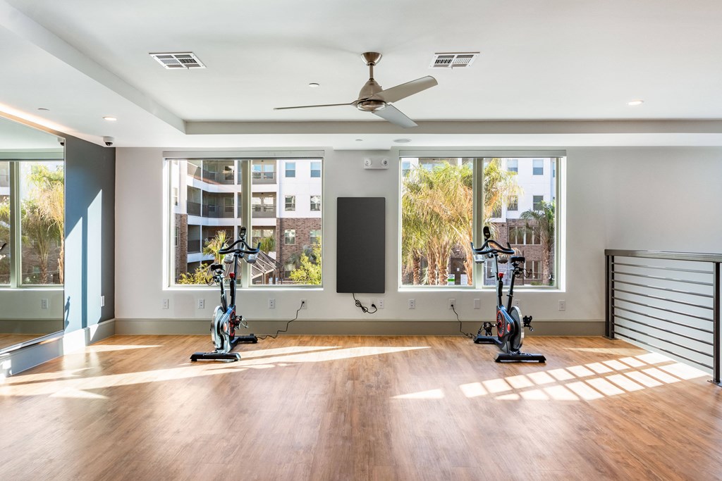 a workout room with three exercise machines and a ceiling fan