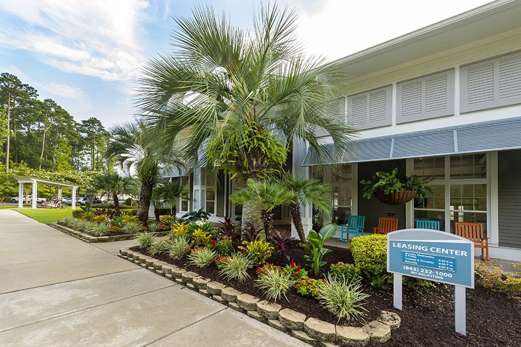 a building with a leasing center sign in front of a palm tree