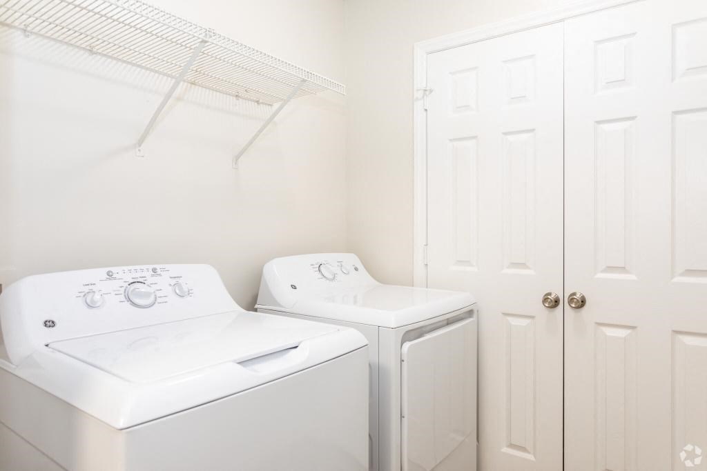 a white laundry room with two white machines and a white closet