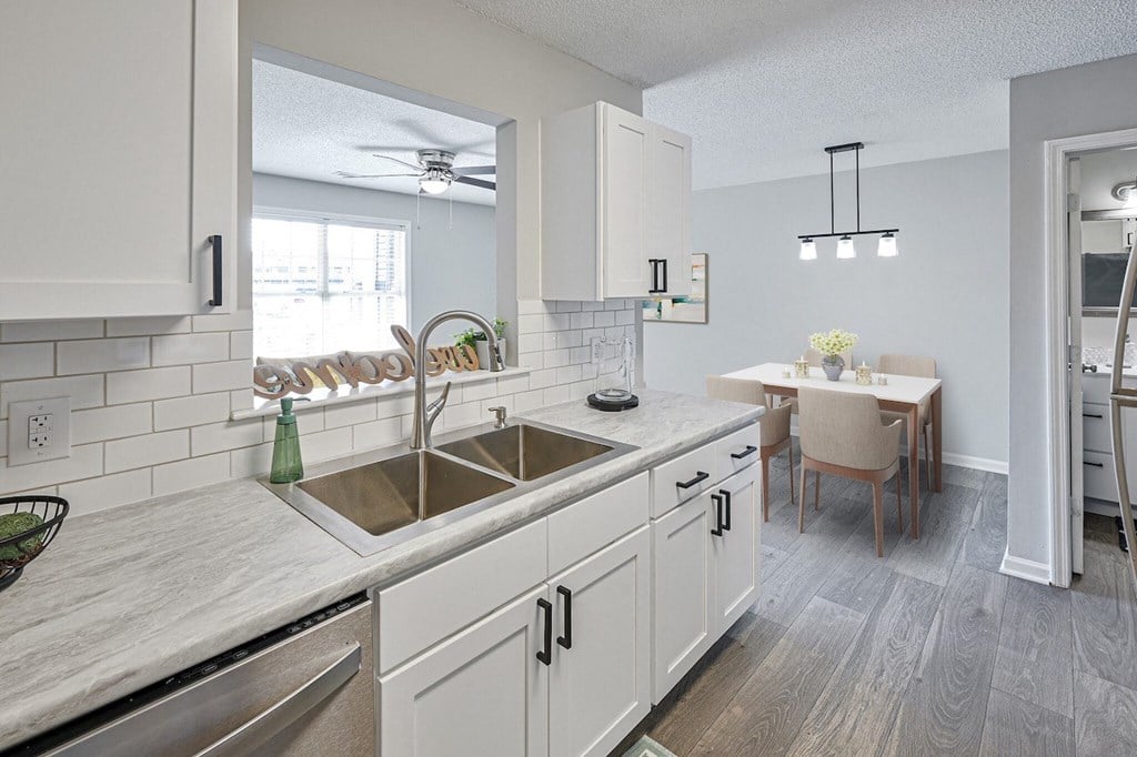 an open kitchen and dining room with white cabinets and a sink
