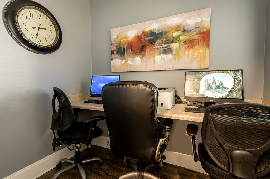 a home office with two computers and a clock on the wall
