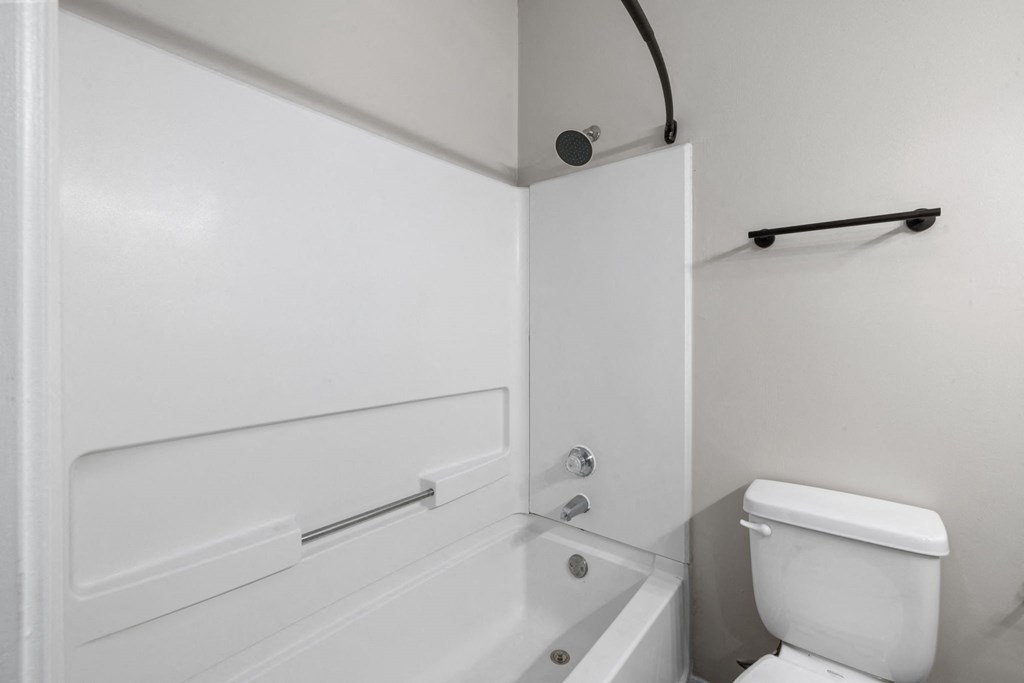 a white bathroom with a white toilet and a bath tub