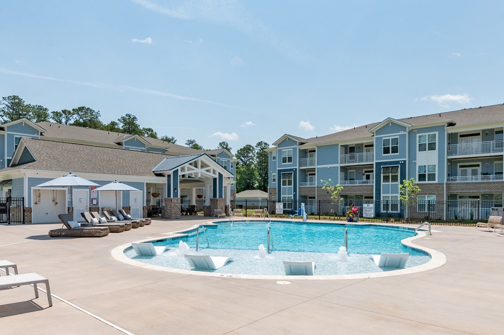a swimming pool with lounge chairs in front of an apartment building