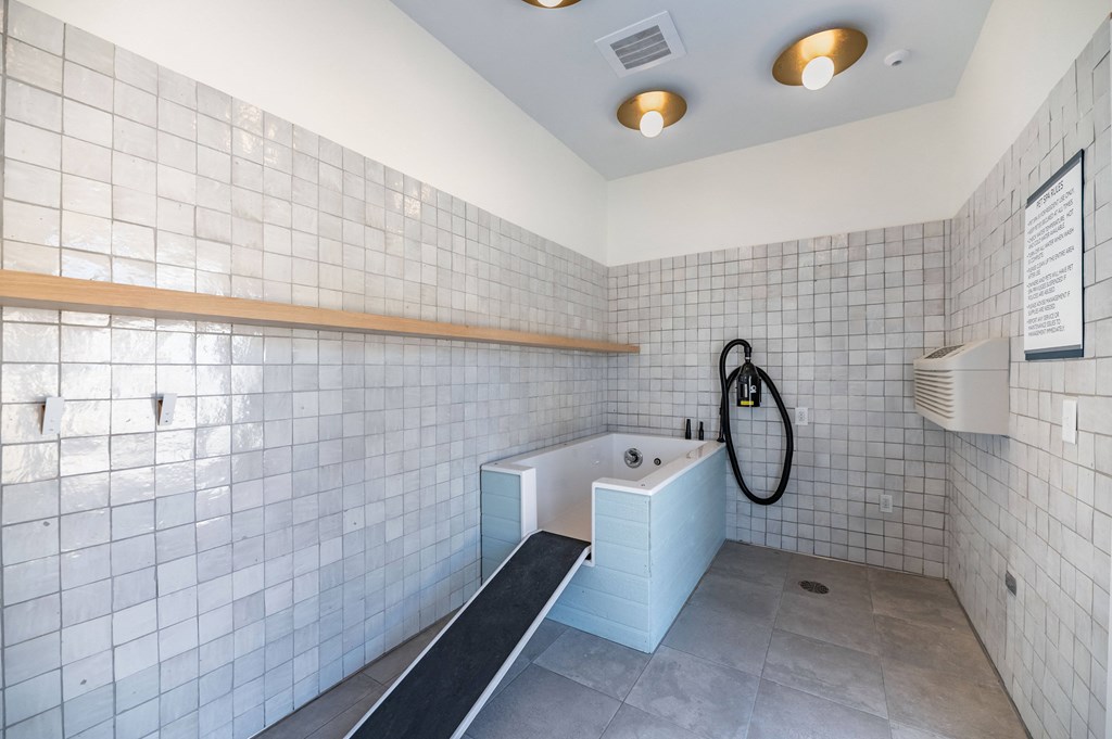 a large white tiled bathroom with a tub and a sink
