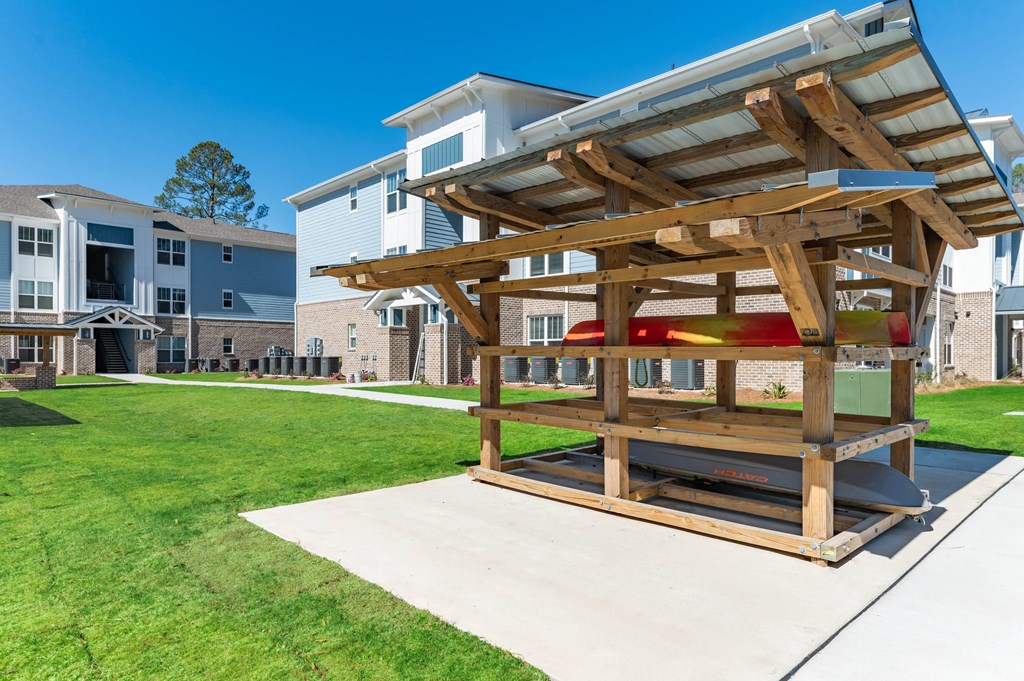 a picnic table with a wooden structure on a sidewalk in front of some apartments