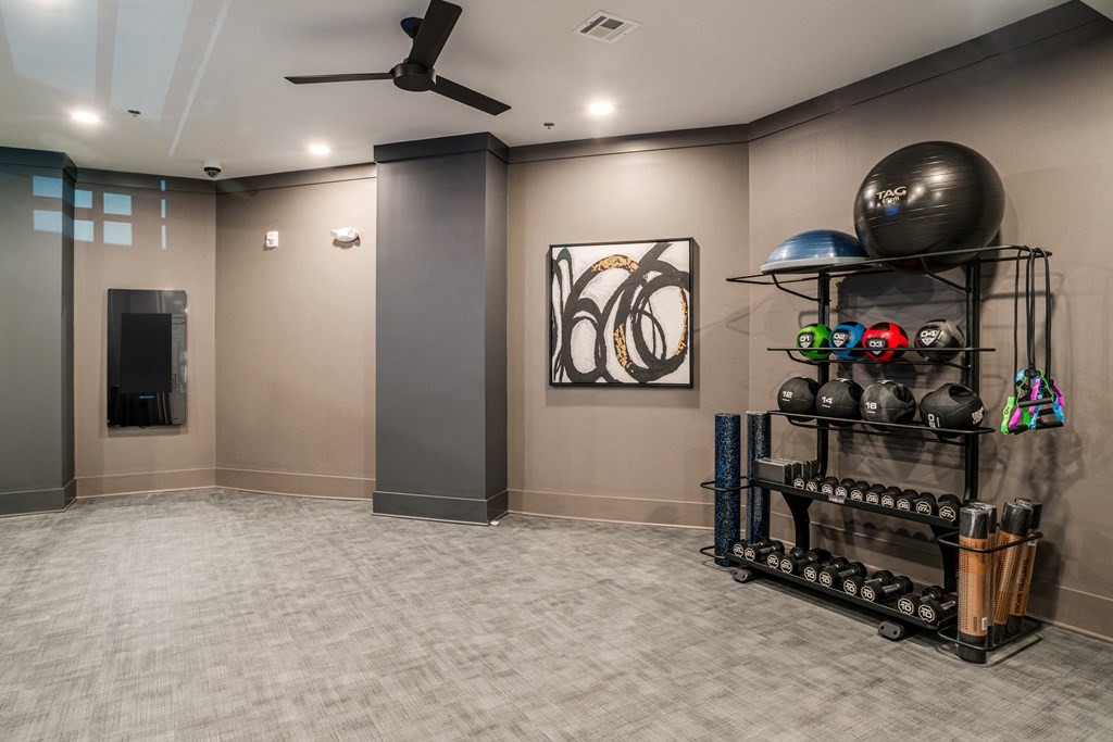 a workout room with a large ball and a rack of weights