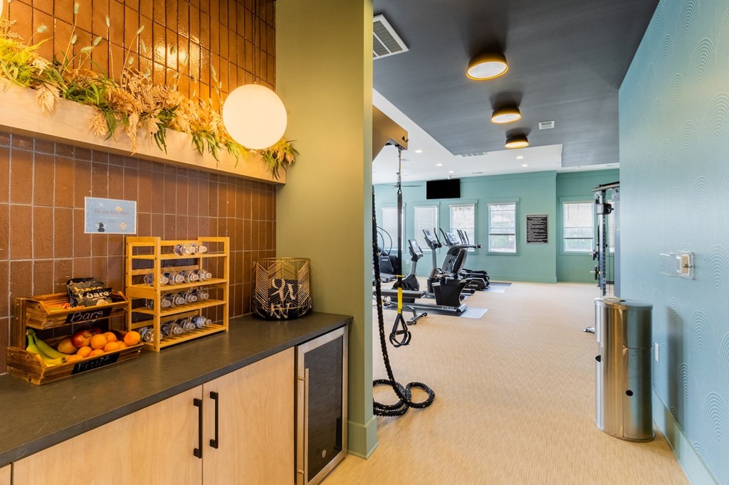 a room with a counter and a row of exercise machines on the left and a wall with