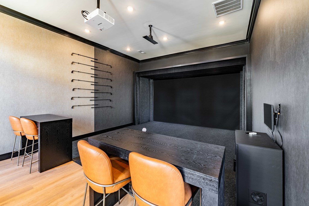 A black desk with orange chairs in a room with a black screen.