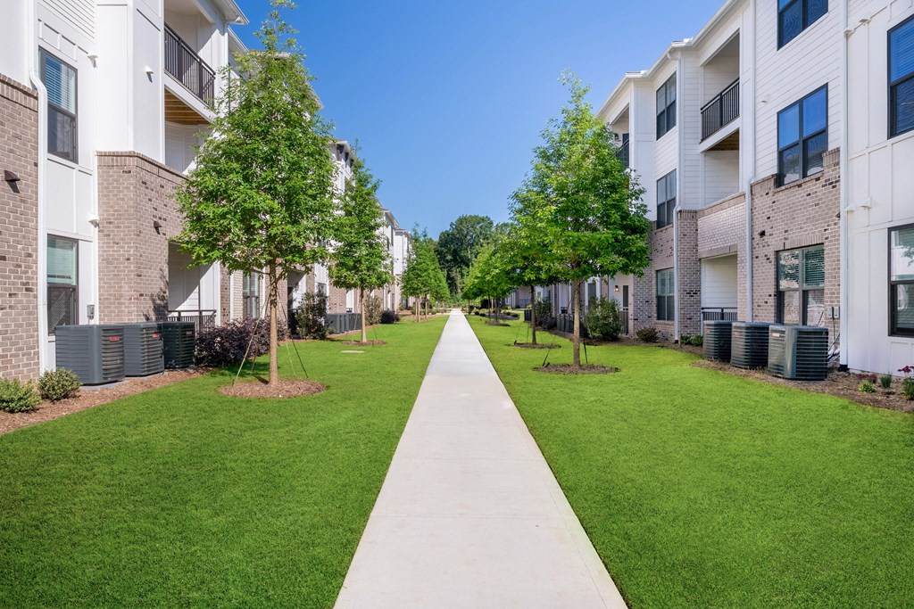 A long concrete walkway separates two rows of apartment buildings.