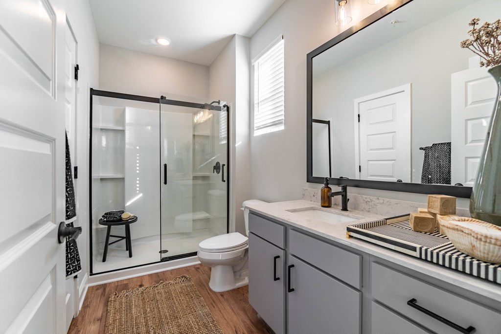 A bathroom with a toilet, sink, and mirror.