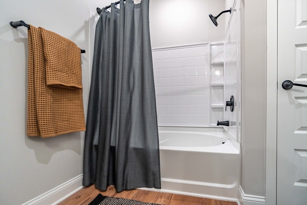 A bathroom with a white tub and a brown towel hanging on the wall.