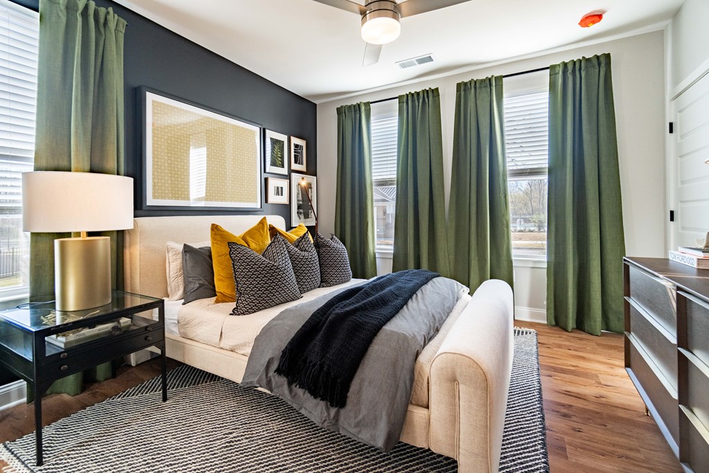 A bedroom with a bed, nightstand, and a table with a lamp.