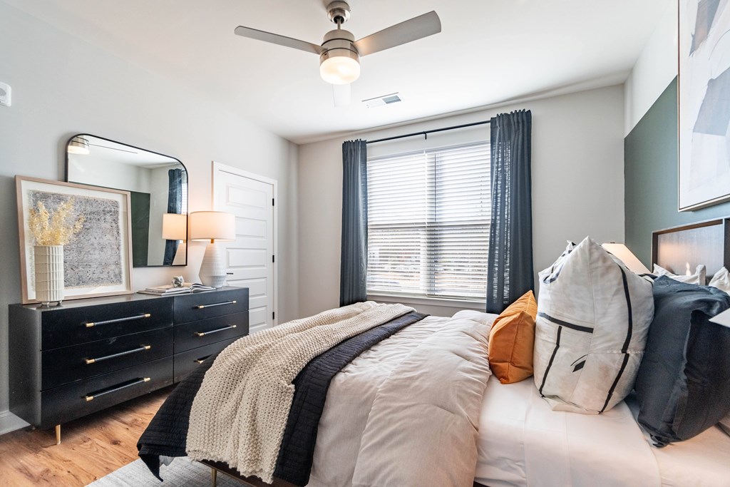 A bedroom with a bed, dresser, and a ceiling fan.