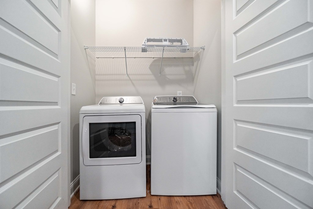 A white microwave oven and a white toaster oven are placed on a wooden floor in a room.