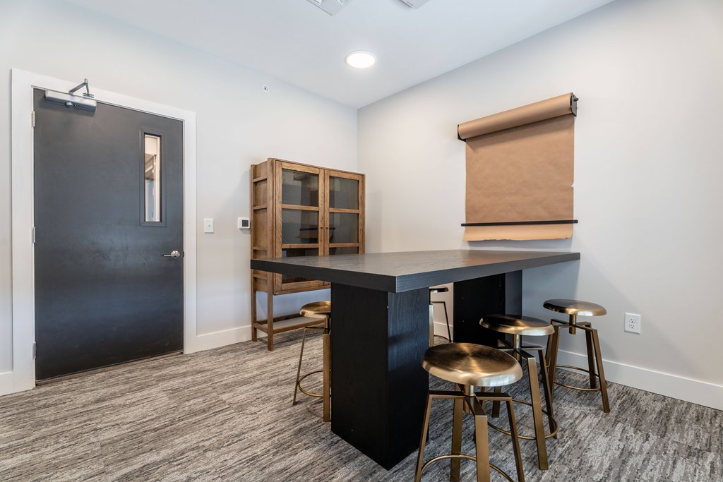 A kitchen area with a black countertop and bar stools.