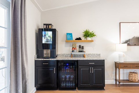 a kitchen with black cabinets and a counter top with a refrigerator and coffee maker