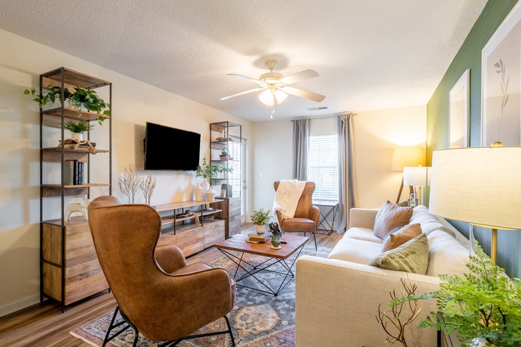 a living room with a couch and chairs and a ceiling fan