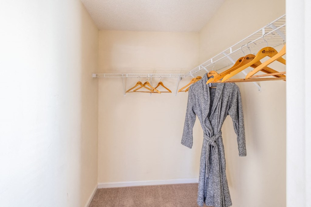 a walk in closet with a coat rack and clothes hangers