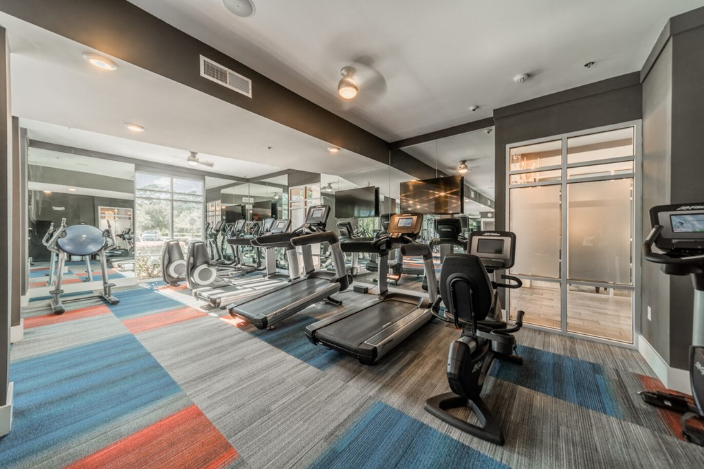 a gym with weights and cardio equipment on the floor and a glass door