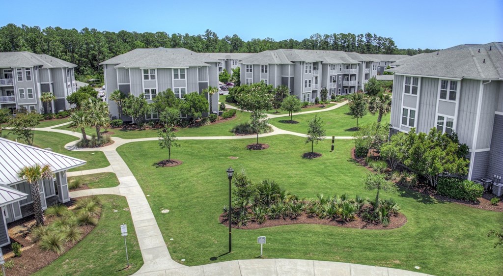 A view of a housing complex with a green lawn and trees.