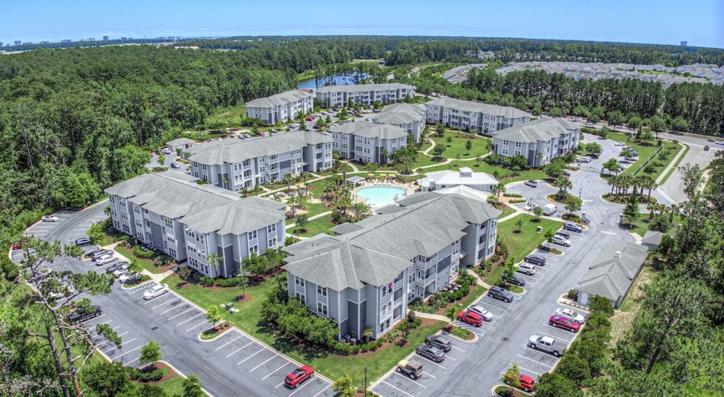 A bird's eye view of a resort with multiple buildings, a swimming pool, and a parking lot.