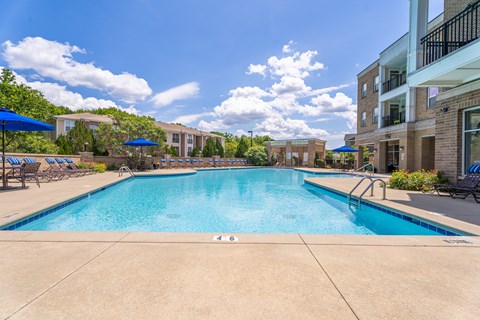 A large swimming pool surrounded by a concrete floor and a metal railing.
