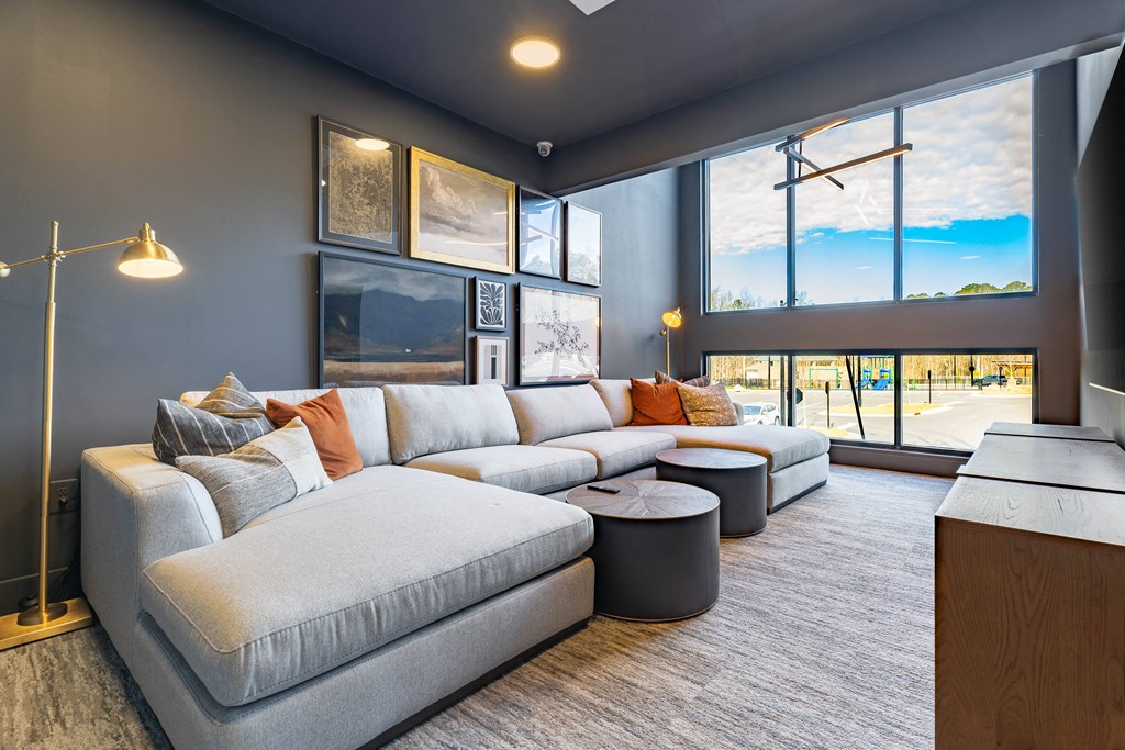 A modern living room with a grey sofa and a large window.