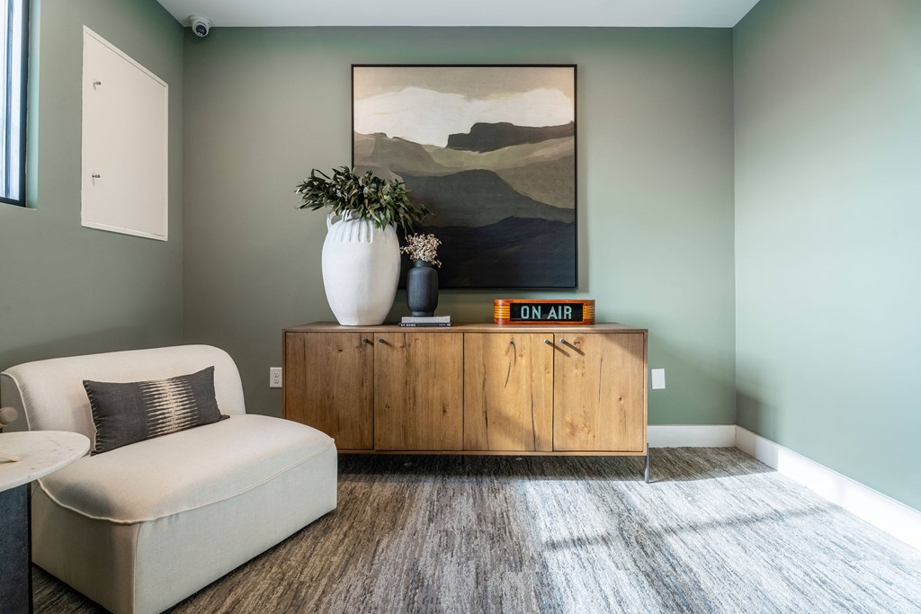 A living room with a white sofa, a wooden cabinet, and a painting on the wall.