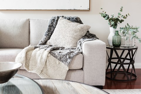 A grey couch with a blanket on it.