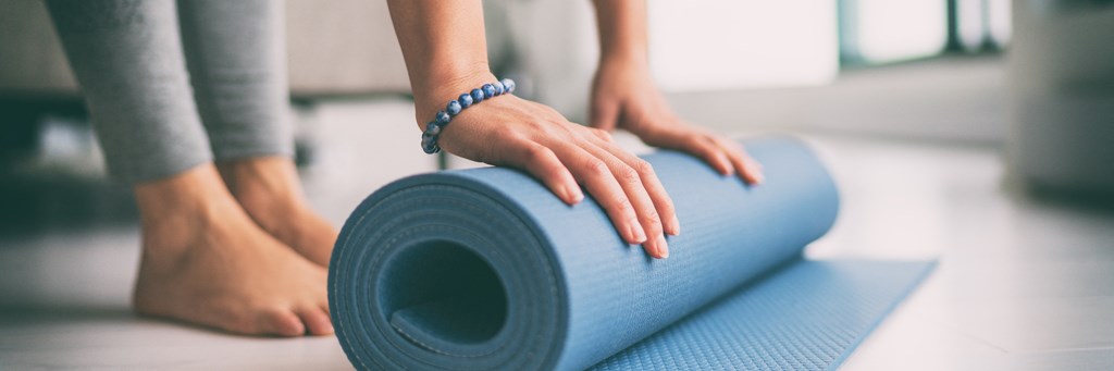 a woman is rolling a yoga mat on a table