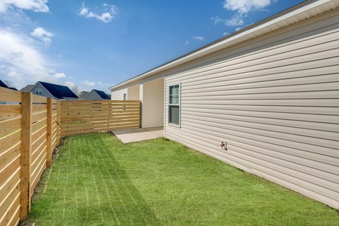 A backyard with a wooden fence and a green lawn.