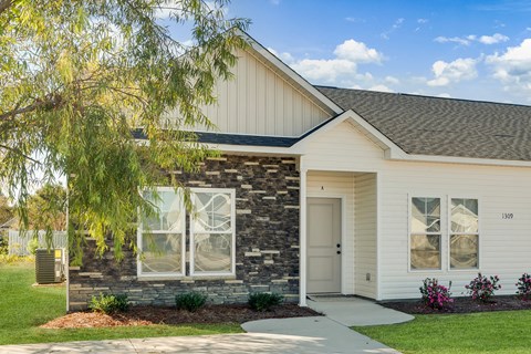 A house with a white exterior and a stone pillar on the front.