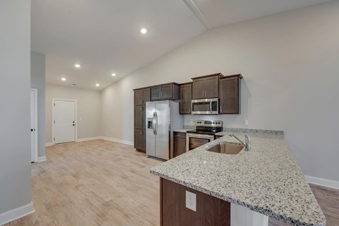 A kitchen with a granite counter top and wooden cabinets.