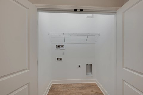 A white hallway with a wood floor and white walls.