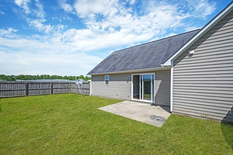 A house with a grey siding and a black roof with a small window and a door.