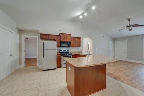 A kitchen with a refrigerator, microwave, oven, and sink.