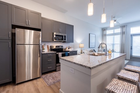 A modern kitchen with a stainless steel refrigerator and a granite countertop.