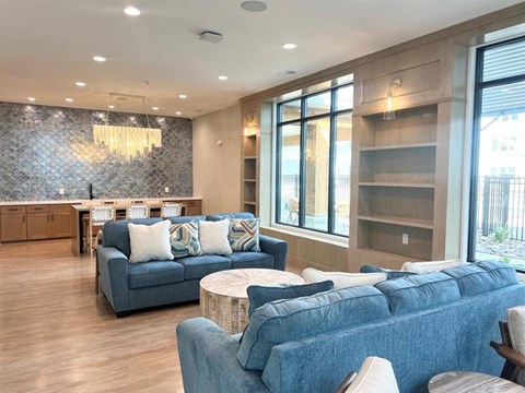 A living room with a blue couch and a stone backsplash.