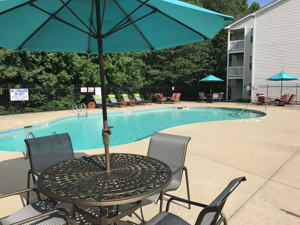 a swimming pool with a table and chairs under an umbrella