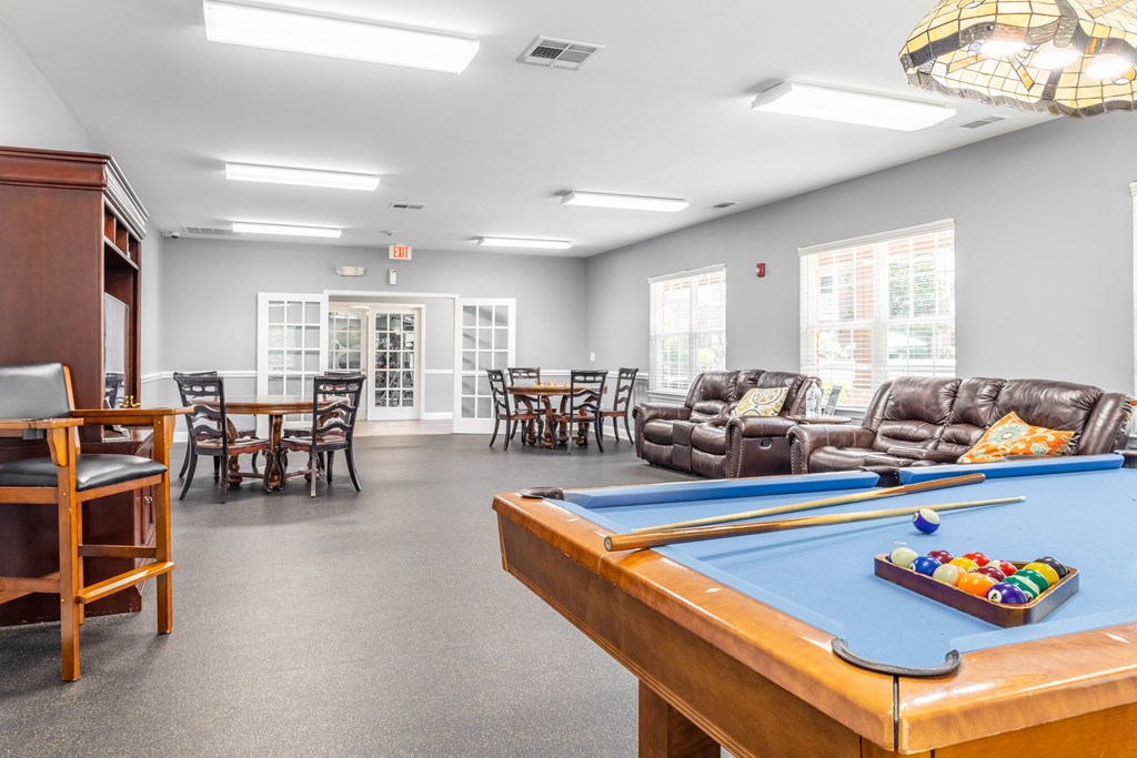 a common room with a pool table and chairs and a dining area