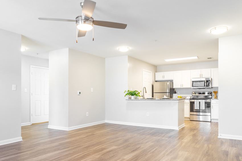 an empty living room and kitchen with a ceiling fan