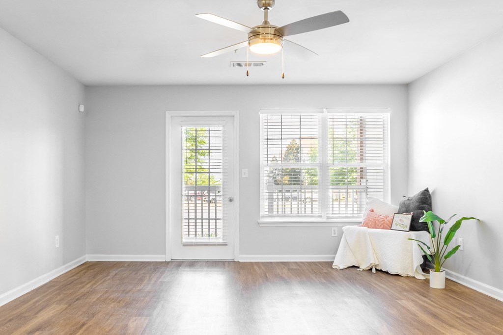 a living room with two windows and a ceiling fan