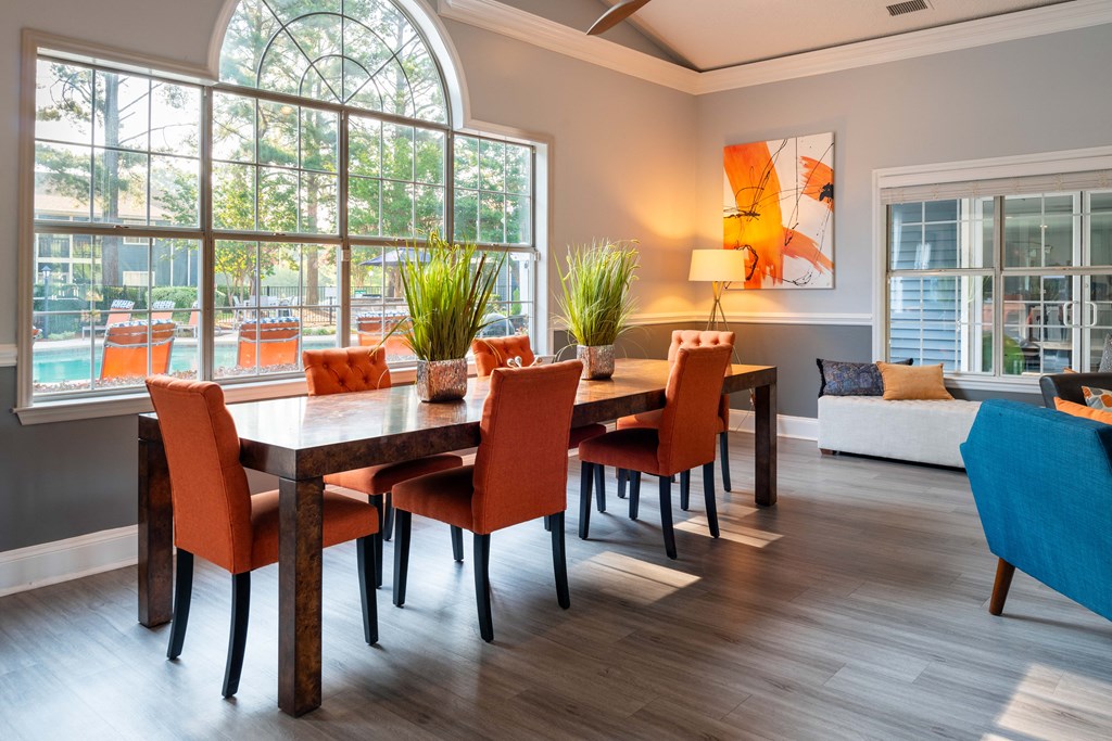 a living room with a large window and a wooden table with orange chairs