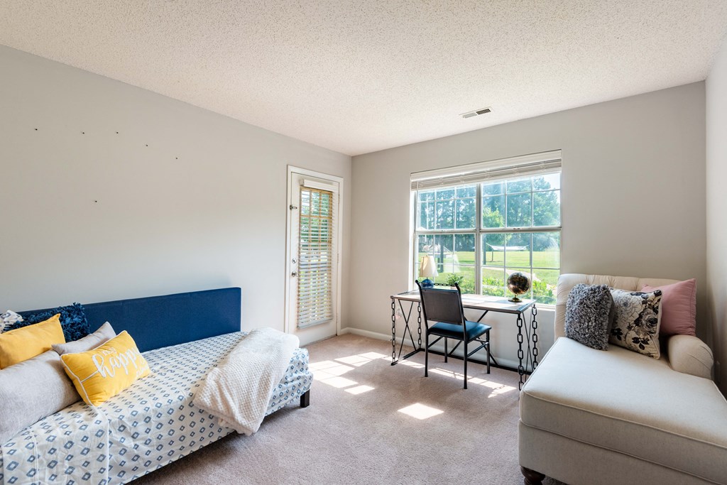 a bedroom with a bed and a chair in front of a window