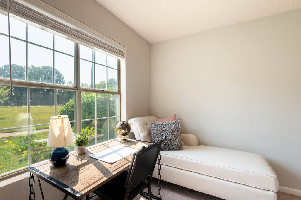 a home office with a large window and a desk with a chair and a lamp