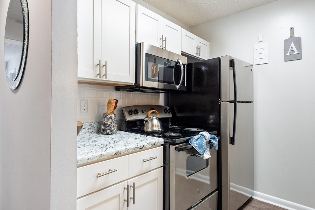 a kitchen with white cabinets and black appliances
