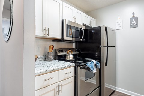 an updated kitchen with white cabinets and a black stove and refrigerator