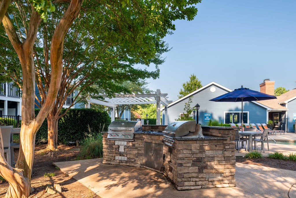 an outdoor kitchen with a grill and umbrella