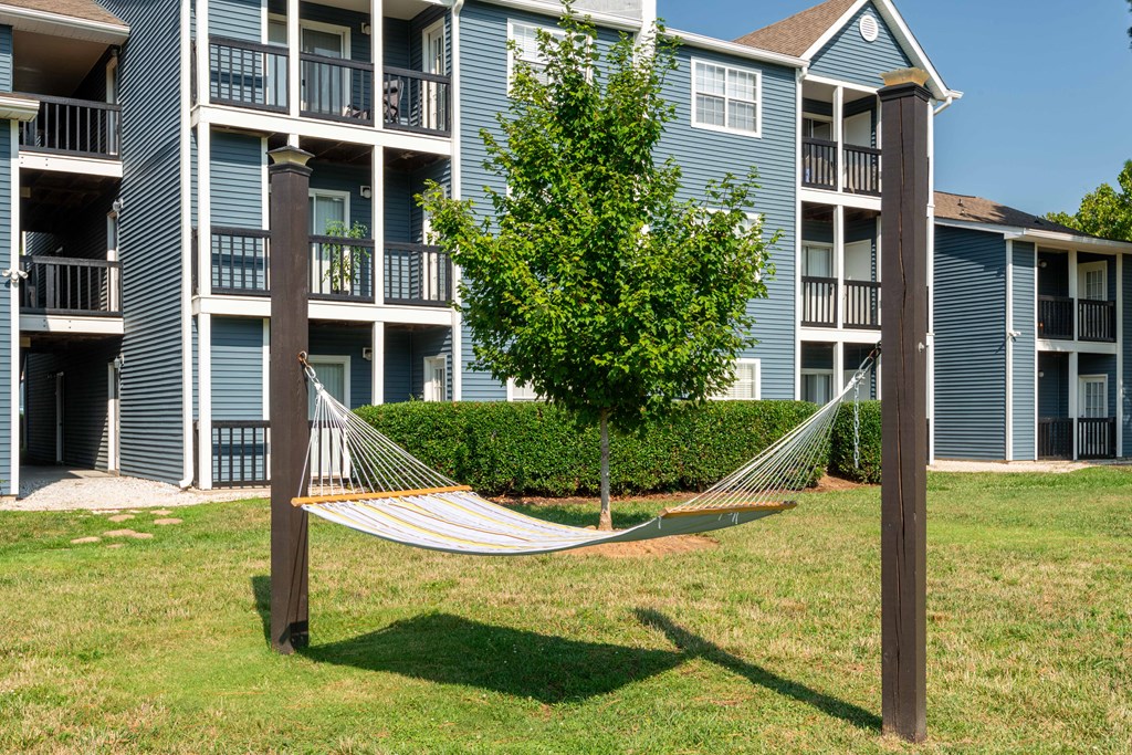 a hammock sits in the grass in front of an apartment building