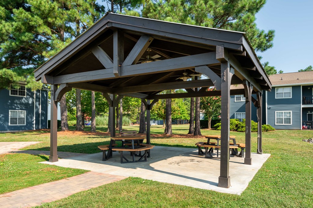 a picnic shelter with two picnic tables in a park